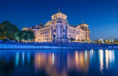panoramic view of famous reichstag building, seat of the german parliament (deutscher bundestag), with spree river in twilight during blue hour at dusk, berlin mitte, germany