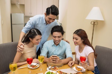 friends looking how young man playing game on his smartphone