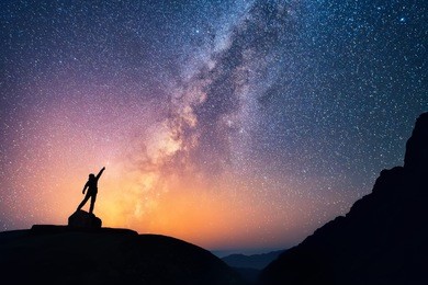 star-catcher. a person is standing next to the milky way galaxy pointing on a bright star.