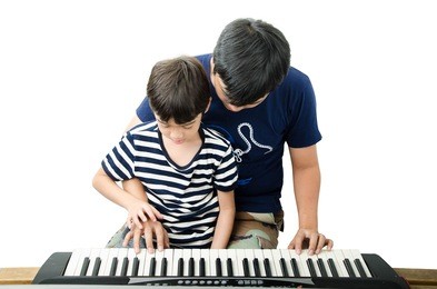 two brothers playing keyboard piano together