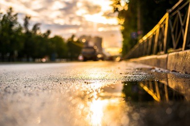 sun after the rain in the city, view of the cars with a level of puddles on the pavement