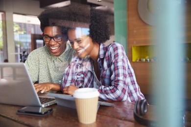 two young businesspeople working on laptop in coffee shop