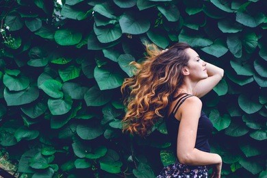 young woman, against background of summer green park, green leaves. running girl with beautiful curly hair