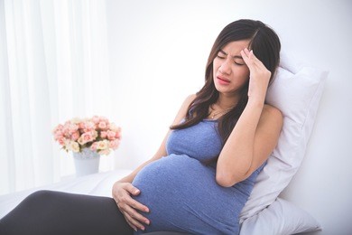 pregnant woman having a headache and morning sickness