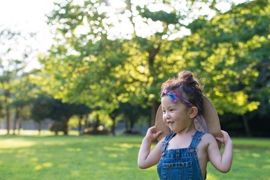 girl playing with too large straw hat