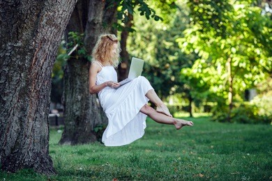 beautiful girl levitates in nature with laptop