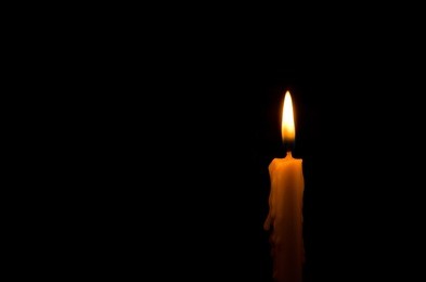 one light candle burning brightly in the black background