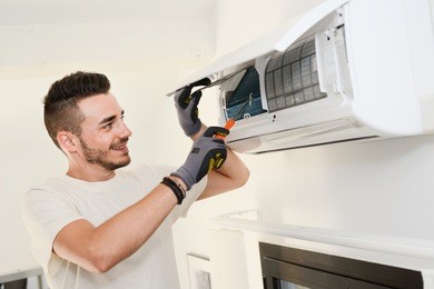 handsome young man electrician installing air conditioning in a client house 