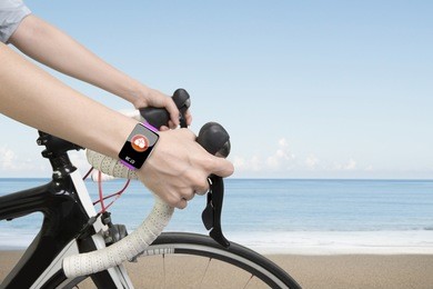 closeup on biking woman hands wearing health sensor smart watch, on sea beach background.