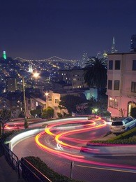 lombard street in san francisco with coit tower, bay bridge and transamerica pyramid in the background