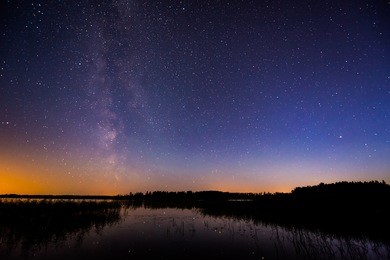 stars and the milky way in the sky over the lake. image in the blue tones