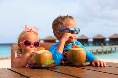little boy and toddler girl drinking coconut cocktail on tropical beach resort, kids luxury travel