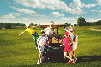children posing near golf car at golf course at summer day