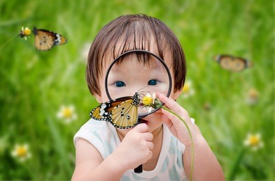  little girl with magnifying glass outdoors in the day time