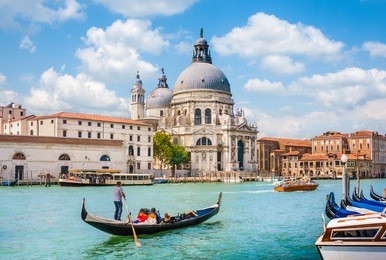 beautiful view of traditional gondola on canal grande with basilica di santa maria della salute in the background on a sunny day in venice, italy