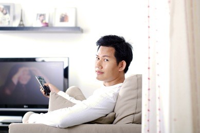 man watching television - hand holding a tv remote