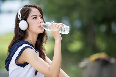 asian woman drinking water after exercise at the park. during the summer