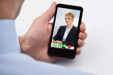 close-up of businessperson videochatting with female colleague on mobile phone