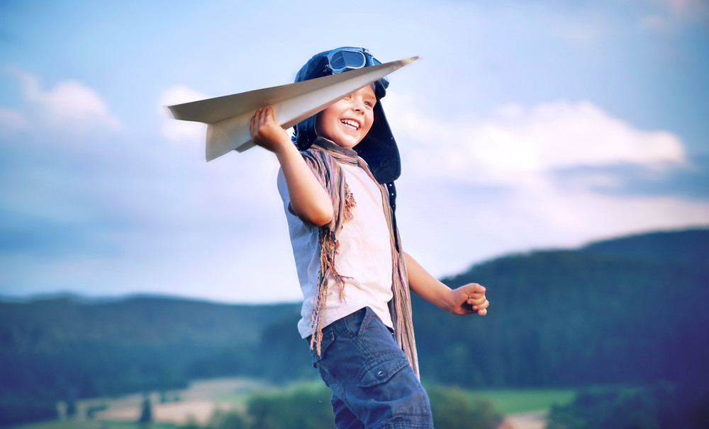 happy kid playing with paper airplane