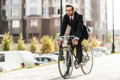 cycling is the way to progress! full length of handsome young businessman looking forward while riding on his bicycle 