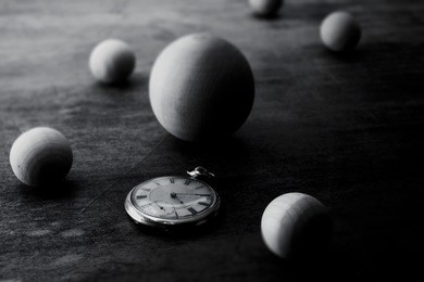 space and time representation.  wooden spheres on a grungy old desk, with an pocket watch. focus on watch. shallow depth of field.