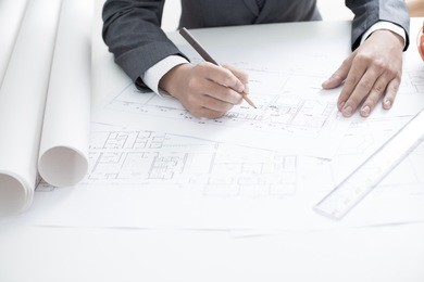closeup cropped image of a young male architect working on blueprints spread out on a table
