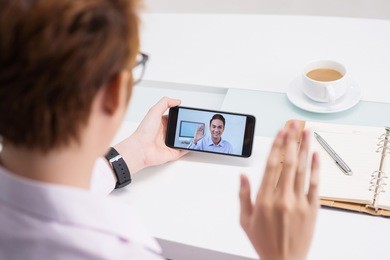 businessman using smartphone to have videocall with his colleague