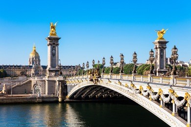 view of the dome des invalides from the pont alexandre iii bridge in the summer morning. pont alexandre iii bridge decorated with ornate art nouveau lamps and sculptures.