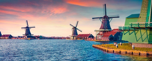 panorama of authentic zaandam mills on the water channel in zaanstad village. zaanse schans windmills and famous netherlands canals, europe. instagram toning.