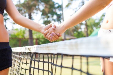 shot of a two young tennis players shaking hands over the net
