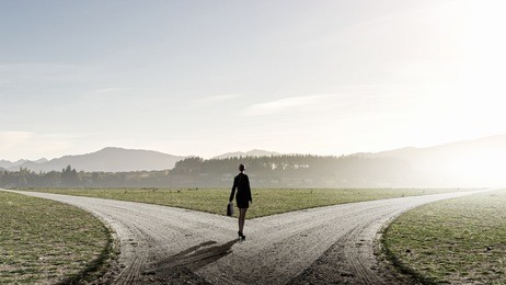 back view of businesswoman standing on crossroads and making choice
