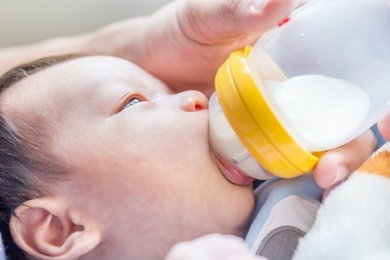 portrait of a newborn drinking milk from a baby bottle 