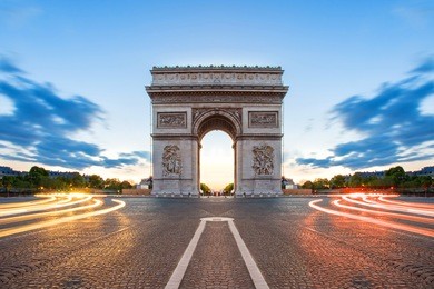 paris street at night with the arc de triomphe in paris, france.