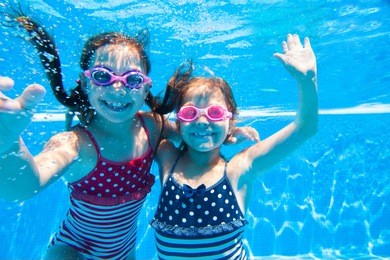 two little girls deftly swim underwater in pool