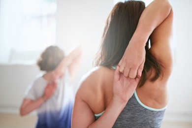 rear view of fit woman doing gomukhasana in yoga class. fitness female holding hands behind their back and stretching. triceps and shoulders workout.
