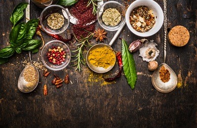 dry colorful  spices in spoons and bowls with fresh seasoning on dark rustic wooden background, top view, border