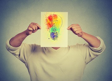 man having brilliant idea colorful lightbulb covering face isolated grey wall background. free thinking, new approach, alternative technology. creativity, imagination, dynamism, intelligence concept