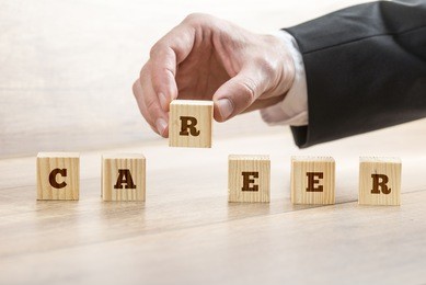 career adviser assembling the word career with six wooden cubes  in a conceptual image of personal guidance towards self realization.