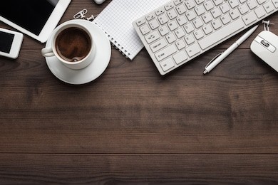office table with notebook, computer keyboard, mouse, cup of coffee, tablet pc and smartphone. copy space