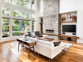 beautiful living room interior with hardwood floors and roaring fire in fireplace in new luxury home. 