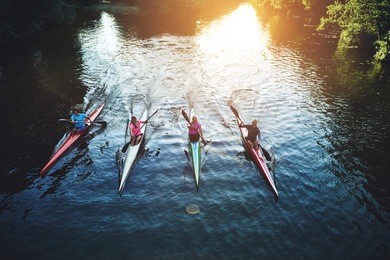 team of rowing people sailing against camera in sunset