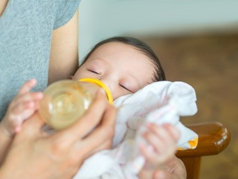 asian mother feeding bottle her baby while baby sleeping.