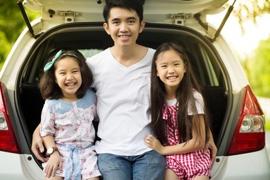 happy asian daughters and father sitting in the car