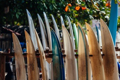 set of different color surf boards in a stack by ocean. weligama. surf boards on sandy weligama beach in sri lanka. on weligama beach surf is available all year around for beginner and advanced.