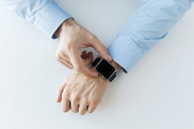 business, technology and people concept - close up of male hands setting smart watch at home