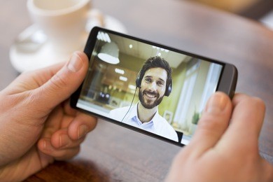 closeup of a male hand holding his smart phone during a skype video