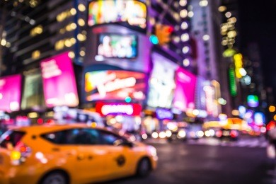defocused blur of times square in new york city with lights at night and taxi cab