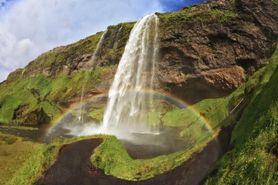  summer sunny day. large rainbow decorates a drop of water. seljalandsfoss waterfall in iceland. the picture was taken fisheye lens