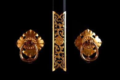 golden japanese style door knob on black wall.