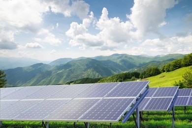 solar panels against mountain landscape against blue sky with clouds 